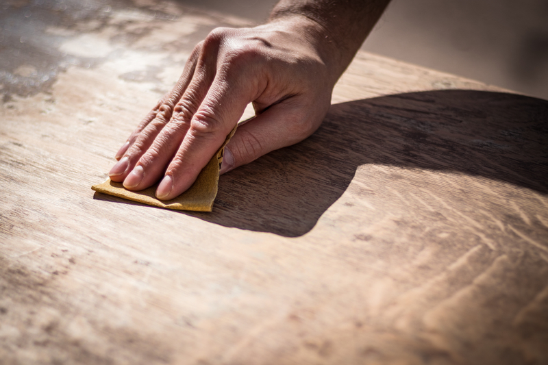Photo of man's hand sanding a piece of wood