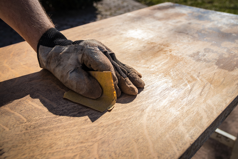 UP close view of a hand sanding a piece of wood
