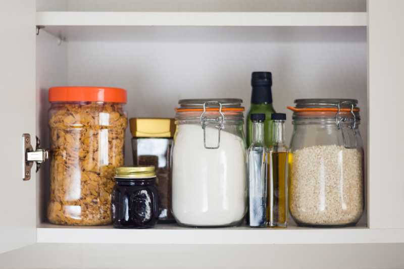 Food containers and other food items organized inside a kitchen cabinet.