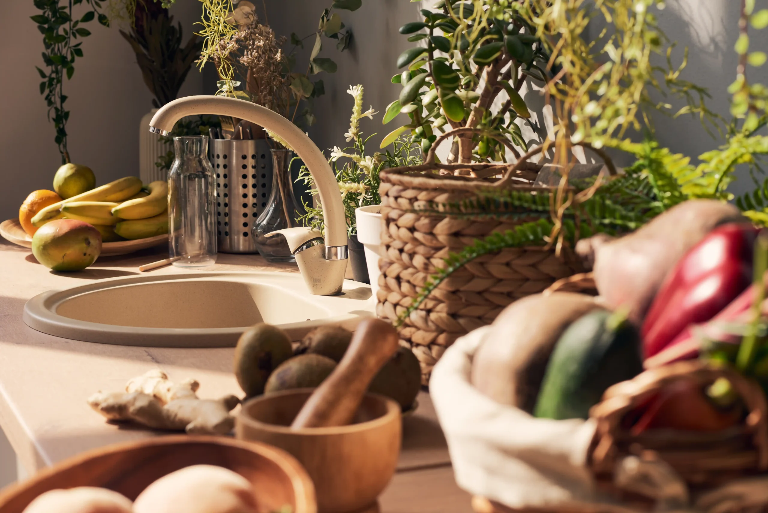 Sunny kitchen counter with fruits, vegetables, and plants. A wicker basket, bananas, kiwis, and potted herbs create a fresh, inviting atmosphere.