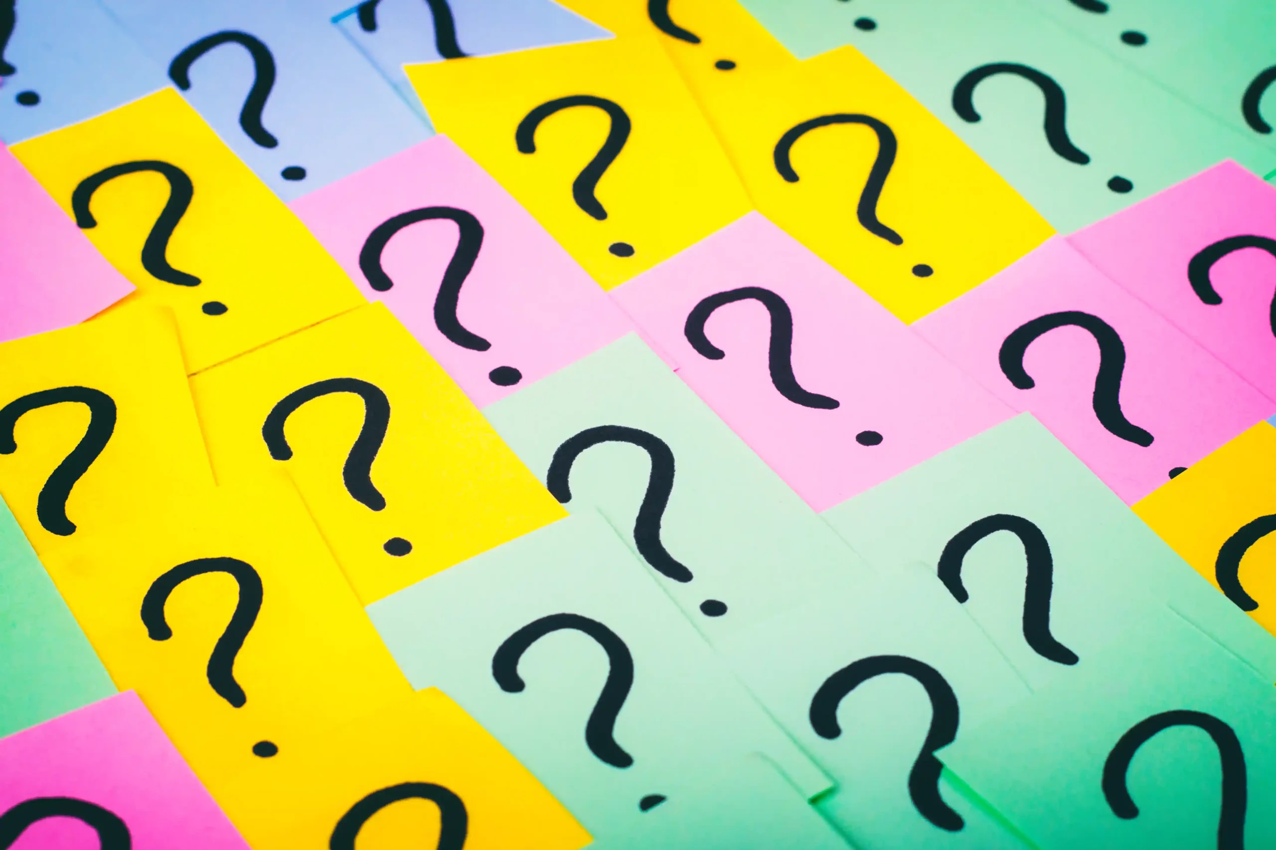 Colorful sticky notes with large black question marks fill the image. The notes are pink, yellow, and green, creating a playful, curious tone.