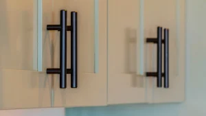 Close-up of two beige cabinet doors with sleek, vertical black handles. The clean design conveys a modern and minimalist aesthetic.